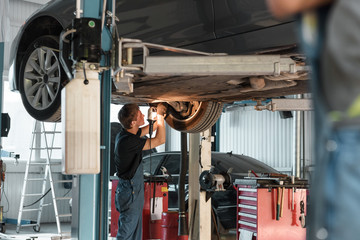 Garage worker repairing car from below