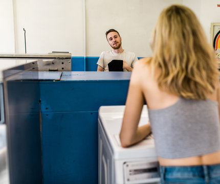 young couple looking and talking in laundromat