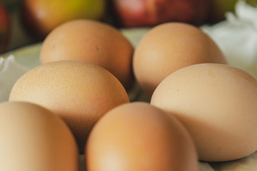 Brown fresh eggs macro shot with apples in back background. Close up