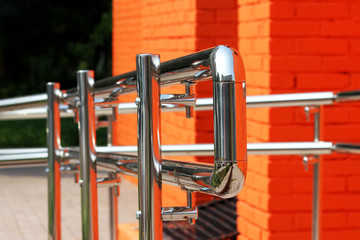 Metal steel handrail with a exit for invalid near the premises. Brick wall painted with orange paint