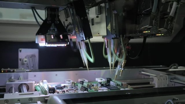 Factory Machine at Work: Printed Circuit Board Being Assembled with Automated Robotic Arm, Surface Mounted Technology Connecting Microchips to the Motherboard. Time Lapse Macro Close-up Footage