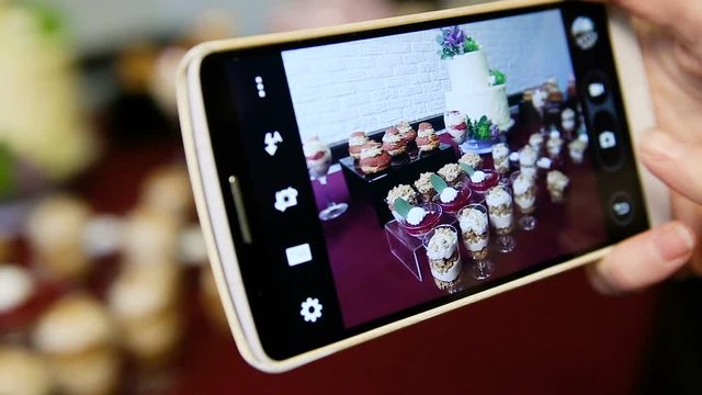 closeup hands take phone pictures of assorted desserts