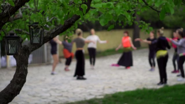 group classes of belly dance in garden area in daytime, women are training and learning