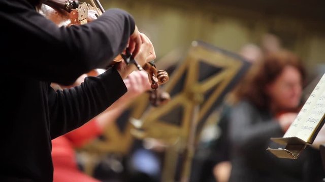 Close up footage of a person performing on a violin during a concert.