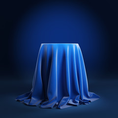 Round podium covered with blue cloth on a blue background. 