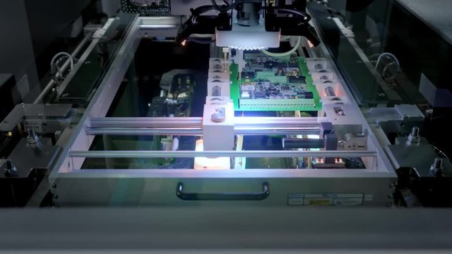 Factory Machine at Work: Printed Circuit Board Being Assembled with Automated Robotic Arm, Surface Mounted Technology Connecting Microchips to the Motherboard. Time Lapse Macro Close-up Footage