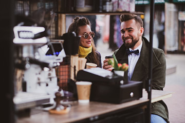 Attractive smart couple is enjoying coffee while sitting outside at small coffeeshop