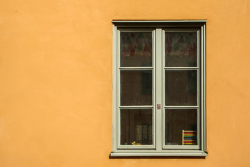Fototapeta na wymiar One white window on a yellow facade of the nordic house in Sweden.