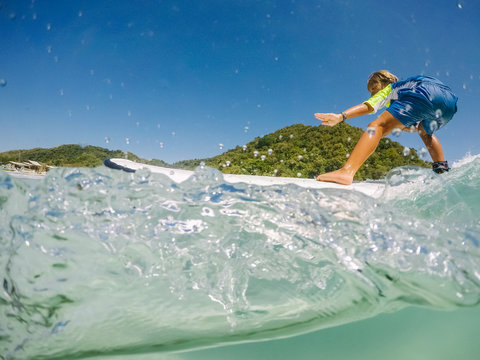 close up of little boy surfing in crystal clear water on lombok