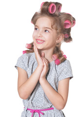 Happy little pretty girl with hair curlers in studio isolated on white background