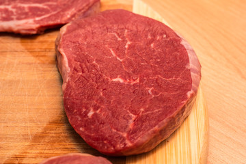 Raw Steaks on a cutting board on a wooden background. fresh meat, top view