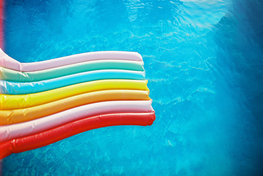 kids on rainbow floaty in blue pool on film