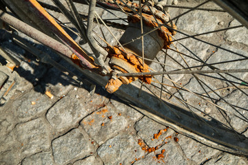 A detail picture of the old unused abandoned bicycle left behind on the street. The chain is rusty and worn away. 