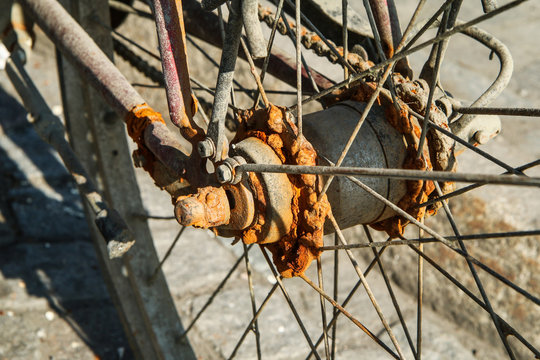 A detail picture of the old unused abandoned bicycle left behind on the street. The chain is rusty and worn away. 