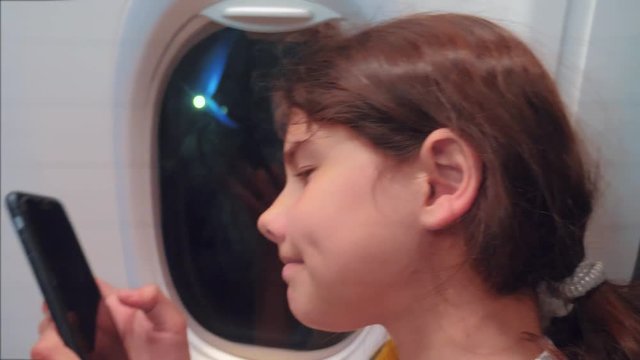 aviation aircraft concept. young girl is flying on a plane inside next to the window is chatting looking in the smartphone in the messenger flight at night by lifestyle airplane