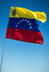 Flag of Venezuela fluttering with a blue sky background.