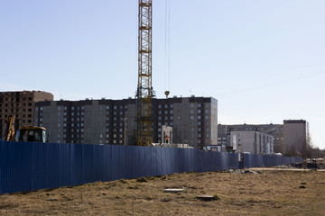 a worker in an orange helmet directs the unloading of concrete slabs with a crane on the construction site of a multi-storey multi-dwelling prefab house. Gatchina. reportage