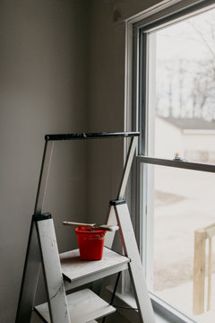 Paintbrush and Paint Bucket Resting on Stepladder in Home