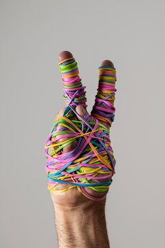 Hand making peace sign covered in rainbow rubberbands