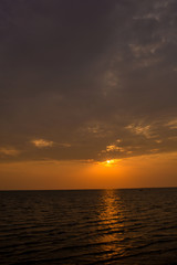 Bright sunset with large yellow sun under the sea surface. sunrise in the sea. Beautiful sunset above the sea. Tropical sunset on the beach.