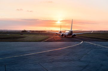 Two aircraft lined up awaiting to enter runway at sunset