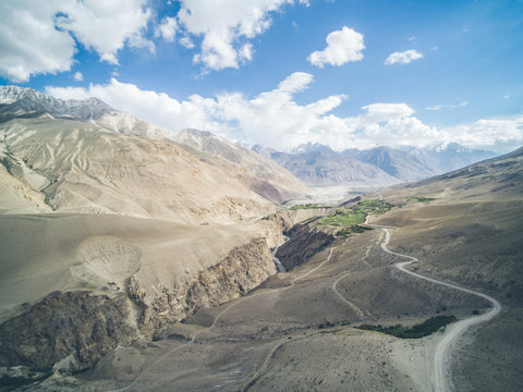 dirt road leading through the pamir range with the himalay in the back