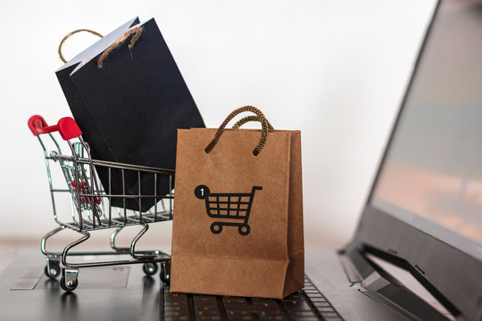Paper shopping bags and shopping cart on laptop. Online Shopping and e-commerce concept