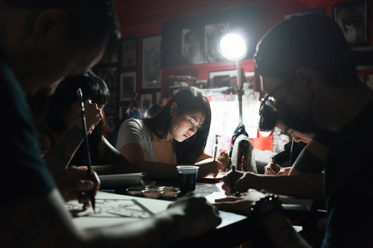 Group of professionals tottooers designing tattoos in studio
