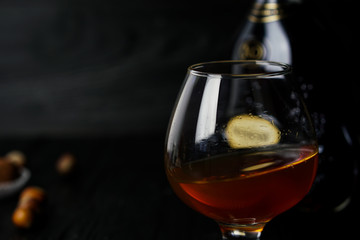 Cognac in a glass on a wooden dark background with truffles and hazelnuts