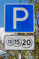 Road sign Paid parking against green trees and blue sky in sunny day closeup