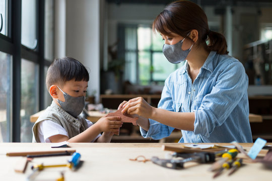 Carpenter wearing mask working with her son in workshop
