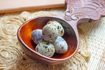 Fresh raw quail eggs in wooden spoon on rustic straw and wooden vintage background