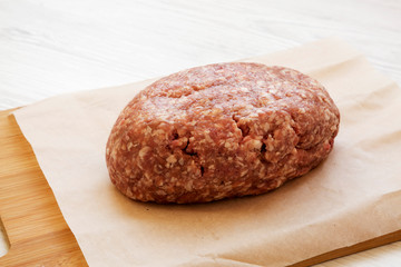 Fresh raw grass fed ground beef on a bamboo board, side view. Closeup.