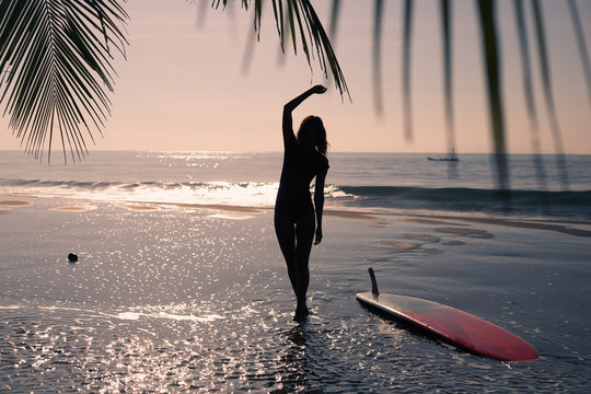 Woman walking along the beach at sunset