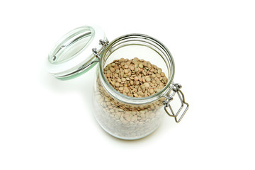 The green lentils stored inside the closable glass bottle isolated on a white background. 