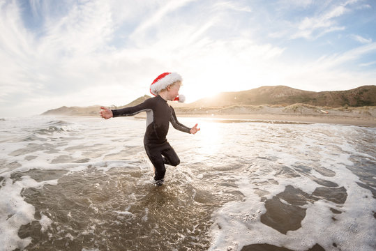 Happy child spinning in water at a beach in New Zealand