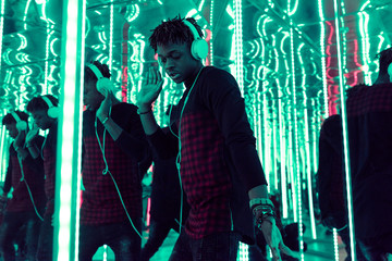 Portrait of young man with headphones dancing in neon labyrinth