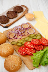 Cheese burger ingredients on a white wooden background, side view. Close-up.