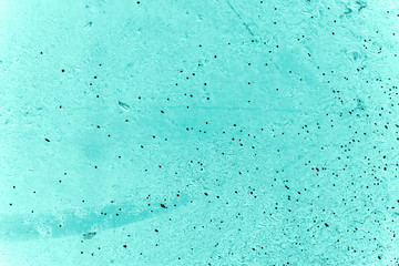 Vintage azure background. Rough painted wall of turquoise color. Imperfect plane of cyan colored. Uneven old decorative toned backdrop of aqzure tint. Texture of teal hue. Ornamental stony surface.