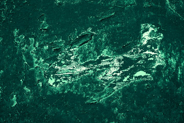 Vintage green background. Rough painted wall of emerald color. Imperfect plane of virid colored. Uneven old decorative toned backdrop of green tint. Texture of emerald hue. Ornamental stony surface.