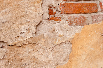 Background rough rustic shabby texture of old wall with yellow cracked plaster and vintage red brick