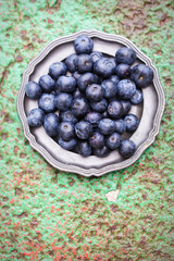 Blueberries on plate on green background 