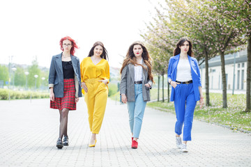 Obraz premium Four adult women walking down the street. Concept of lifestyle, friendship, students