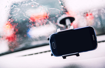 Smart phone on holder, rainy weather seen through wind shield, cellphone with black mock up blank...