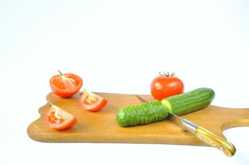 slicing cucumber and tomato with a knife on a board