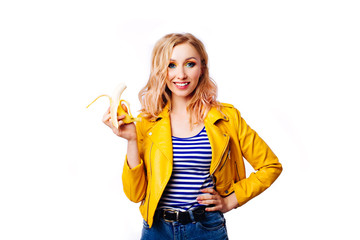 Slim blonde girl with a banana in her hands on an isolated white background.- Image