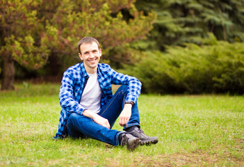 Naklejka na ściany i meble Young man relaxing on grass in summer park