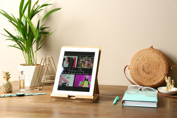 Stylish workplace with modern tablet on table near color wall. Fashion blogger