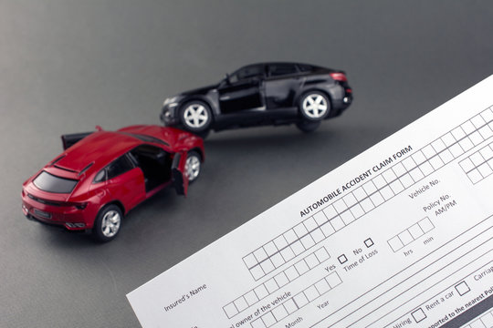 two toy broken cars and car insurance document. compare car insurance concept. gray background