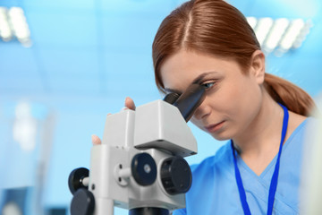Fototapeta premium Female scientist using microscope in chemistry laboratory, space for text